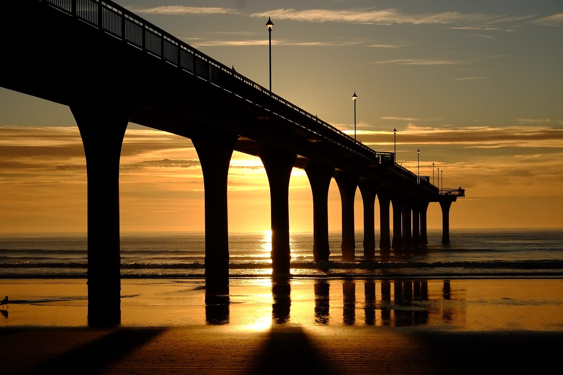 New Brighton Pier silhouetted against a golden sunrise